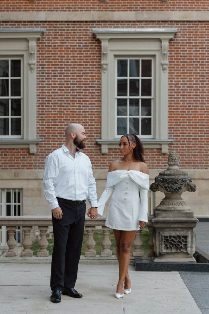 Cheyanne and Keegan holding hands while walking through Osgoode Hall courtyard in Toronto