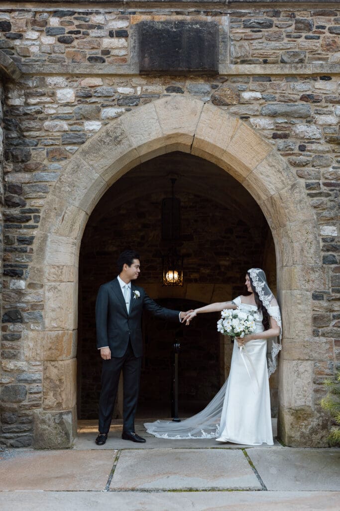 Bride and groom beneath the stone arch at Parque at Ridley Creek
