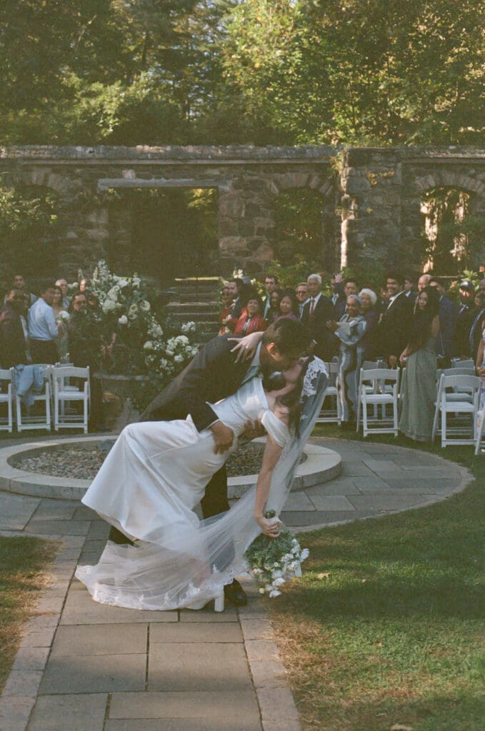 Bride and groom portrait on 35mm film at Parque at Ridley Creek kissing during ceremony 
