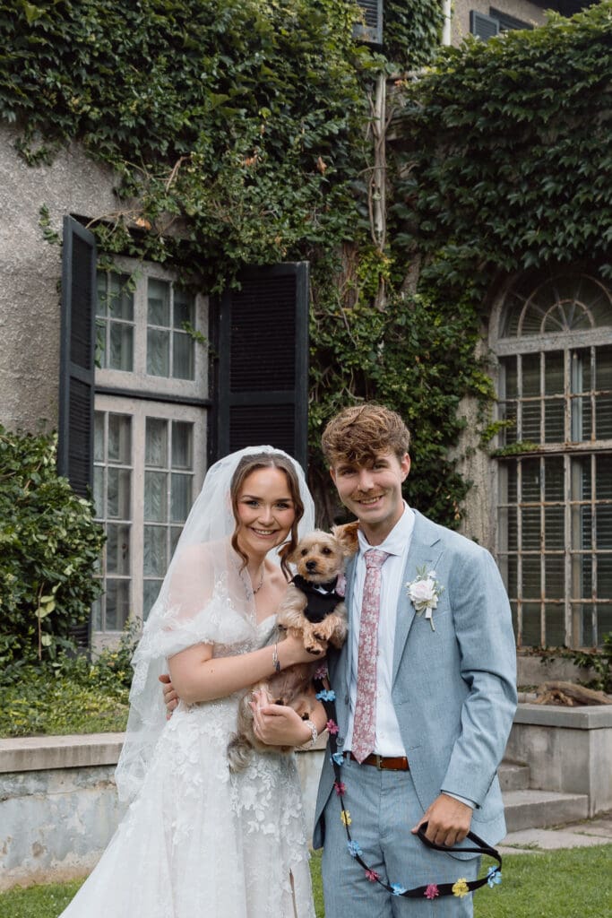 Bride and groom holding their dog during wedding portraits
