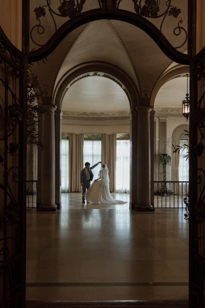 Bride and groom framed by the historic arches inside the Parkwood Estate mansion
