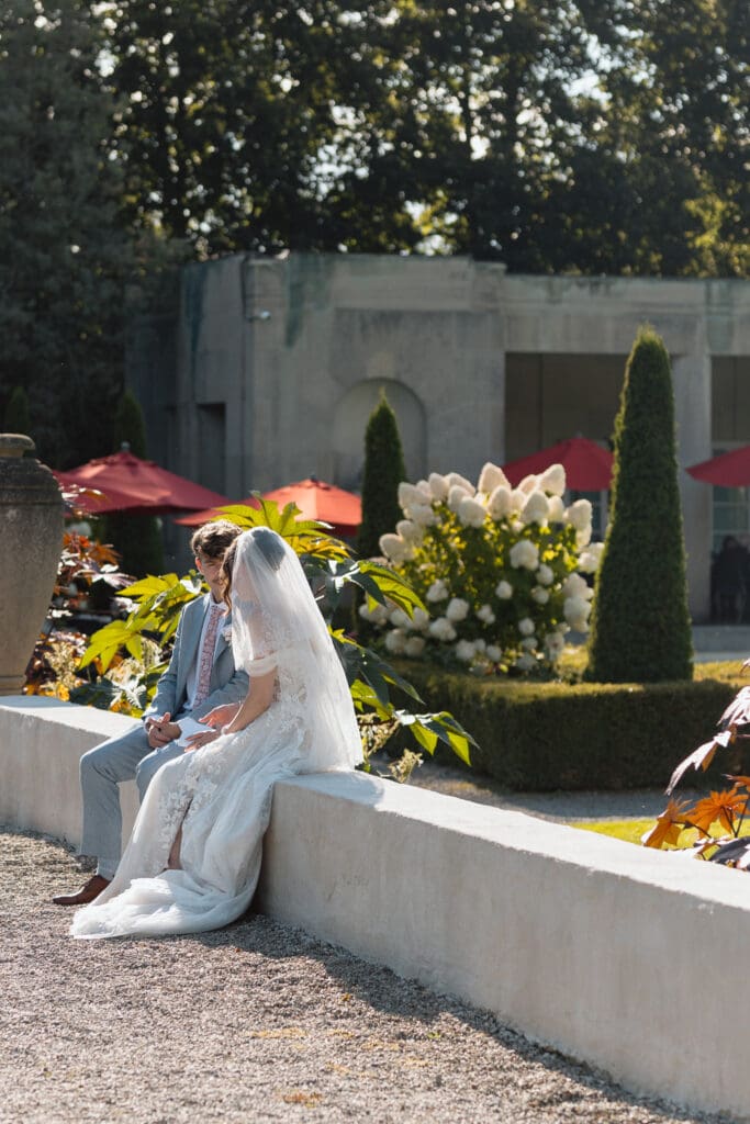 Bride sitting along the stone terrace overlooking the gardens
